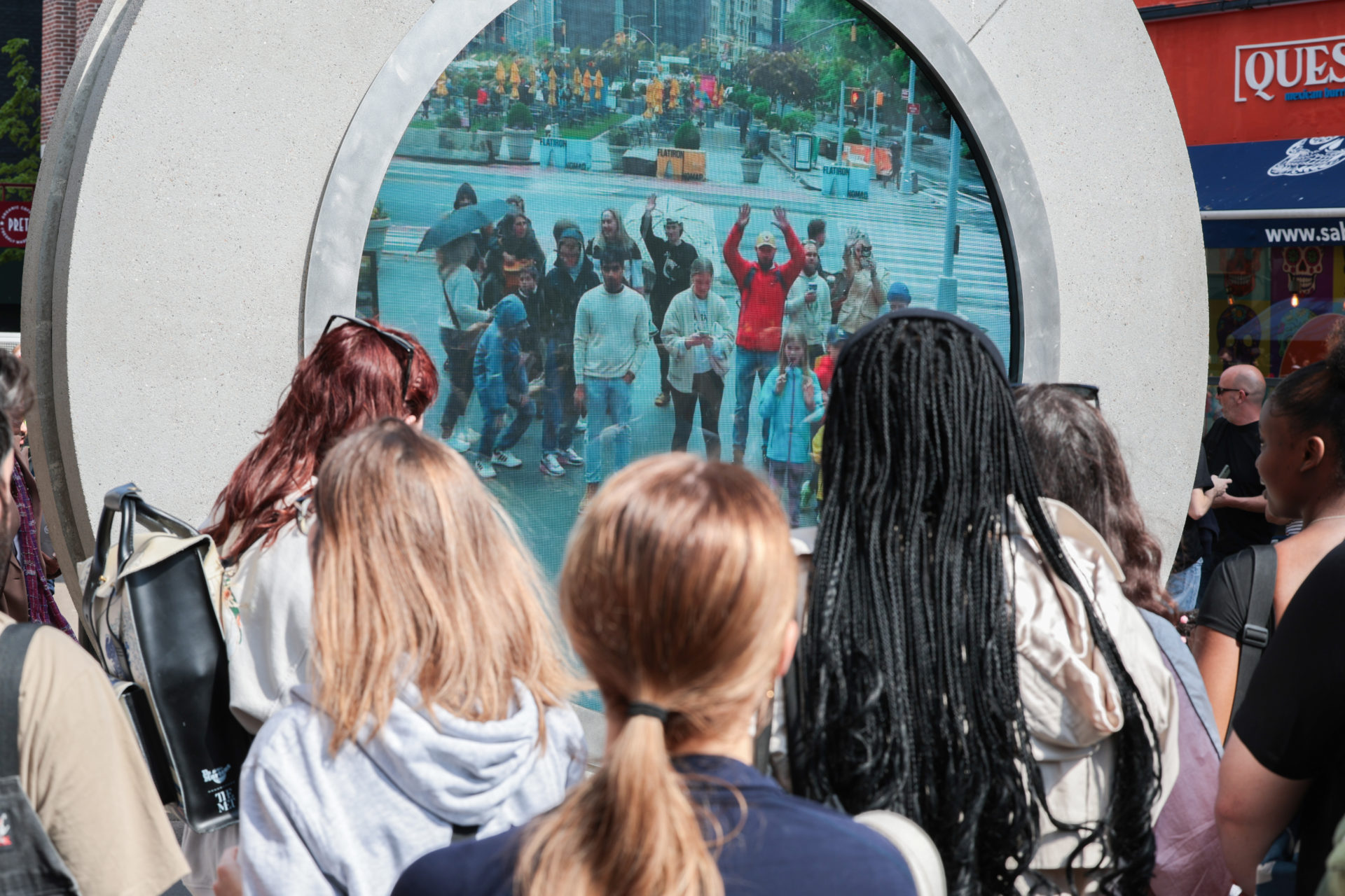 Dubliners enjoy the sun shine as they wave to people in a rainy New York City. The Portal, a new art installation off O'Connell Street, is an on-street sculpture with a 24/7 livestream of both Dublin and New York in either city. 