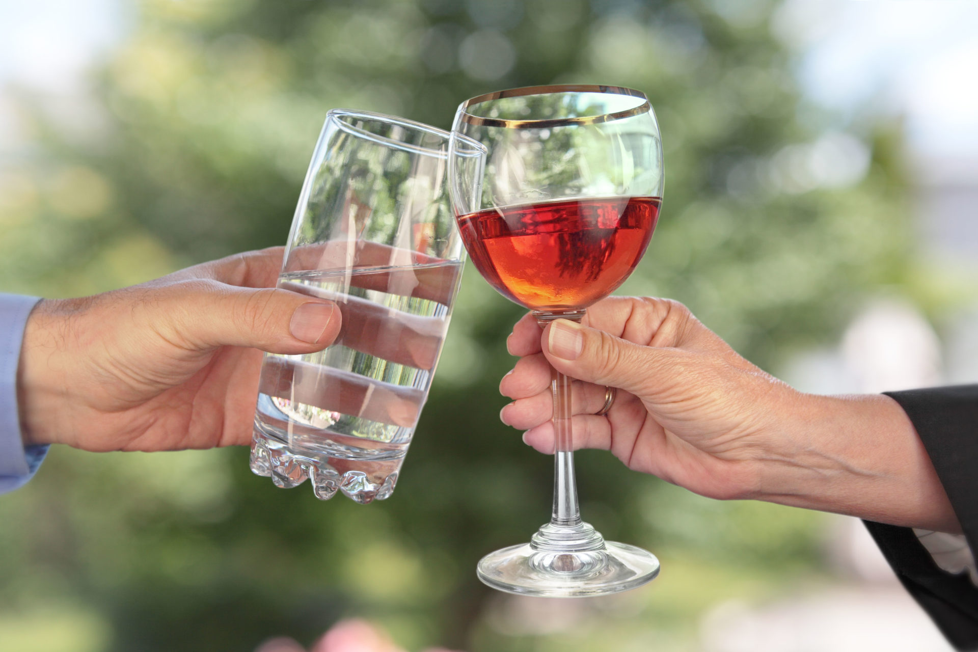 Two hands clink drink glasses together