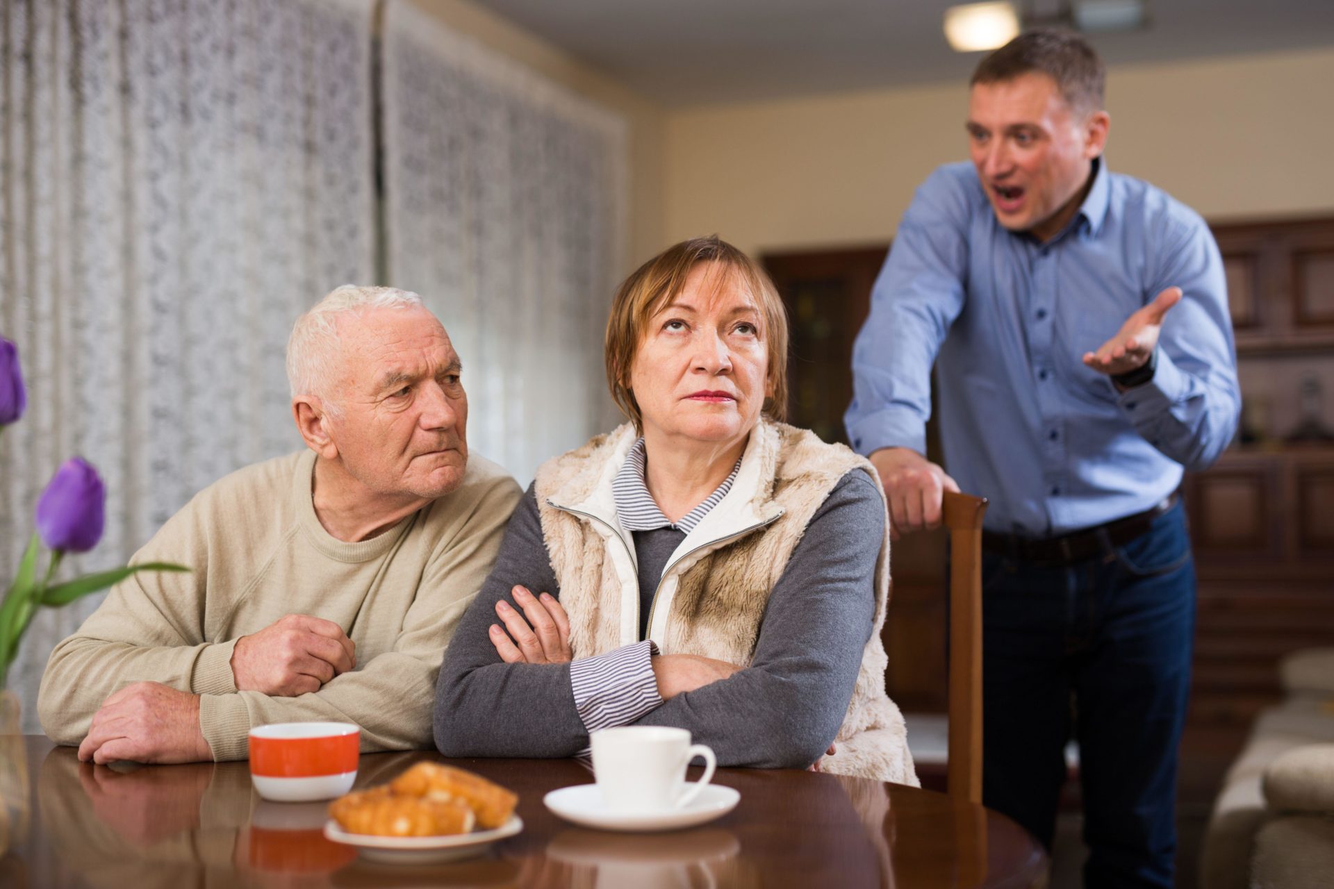 Adult son argues with his elderly parents at home.