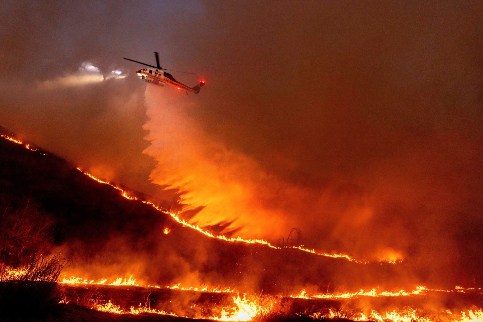 Water is dropped by helicopter on the Kenneth Fire in the West Hills section of Los Angeles. 09/01/2025 (AP Photo/Ethan Swope)