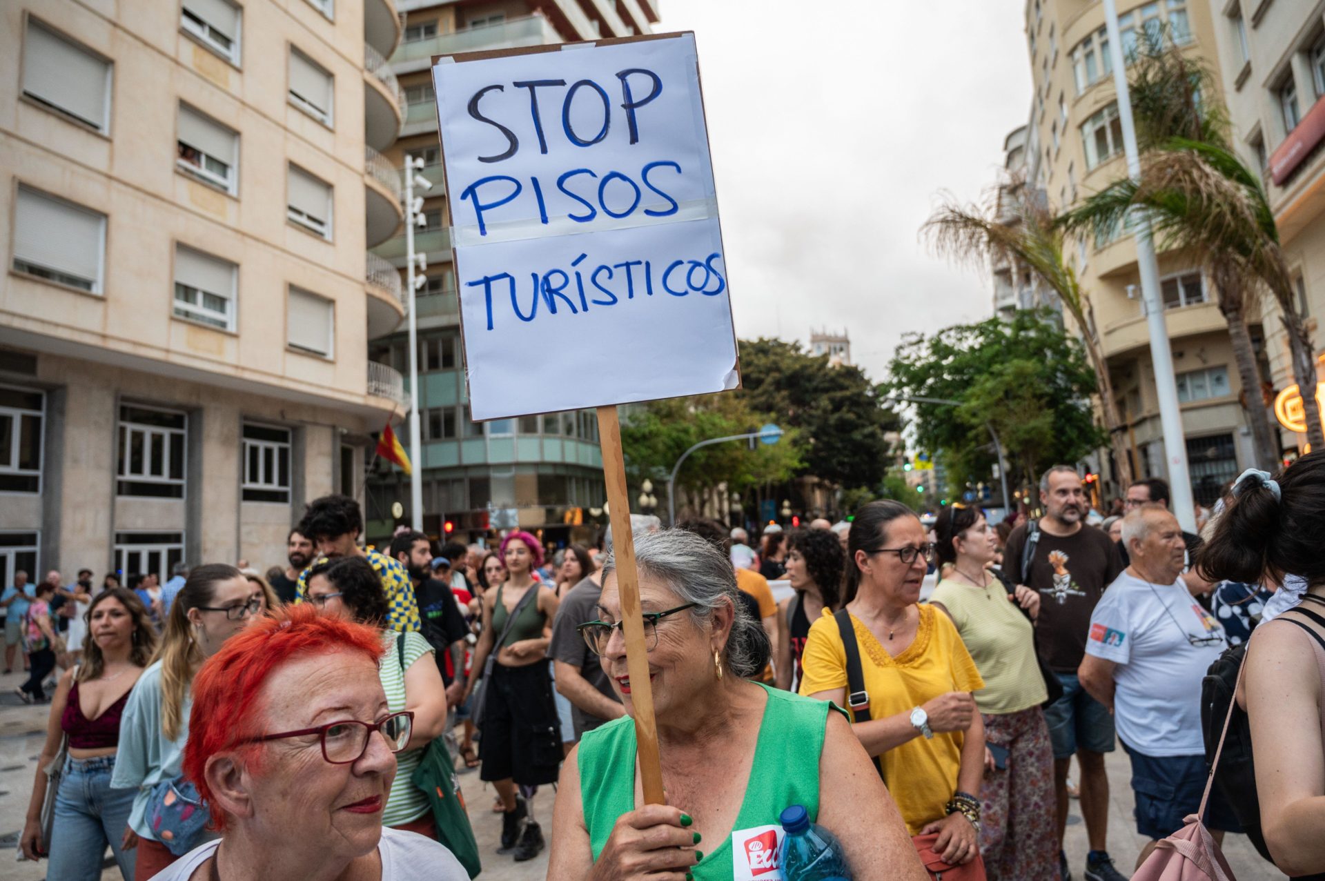 A woman carrying a placard reading "stop tourist apartments" during a protest against mass tourism. 