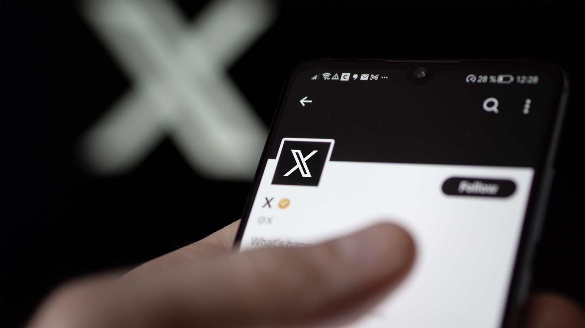 A person holding a phone open on the X app