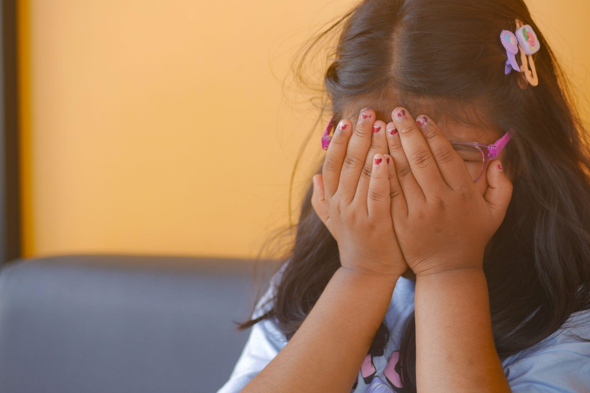 An upset child girl covering her face with hands. Image: Alamy