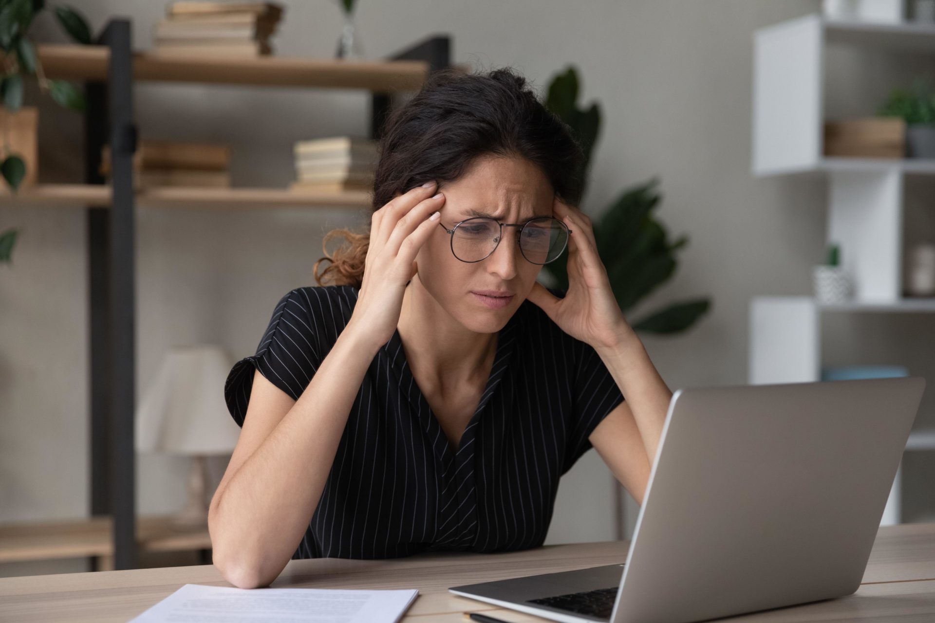 Stressed woman having problems, looking at laptop screen. 