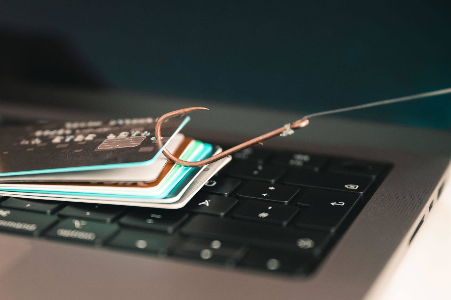 2RBNE0A Visualisation of phishing and online fraud by a phished credit card on a PC keyboard hanging on a fishhook