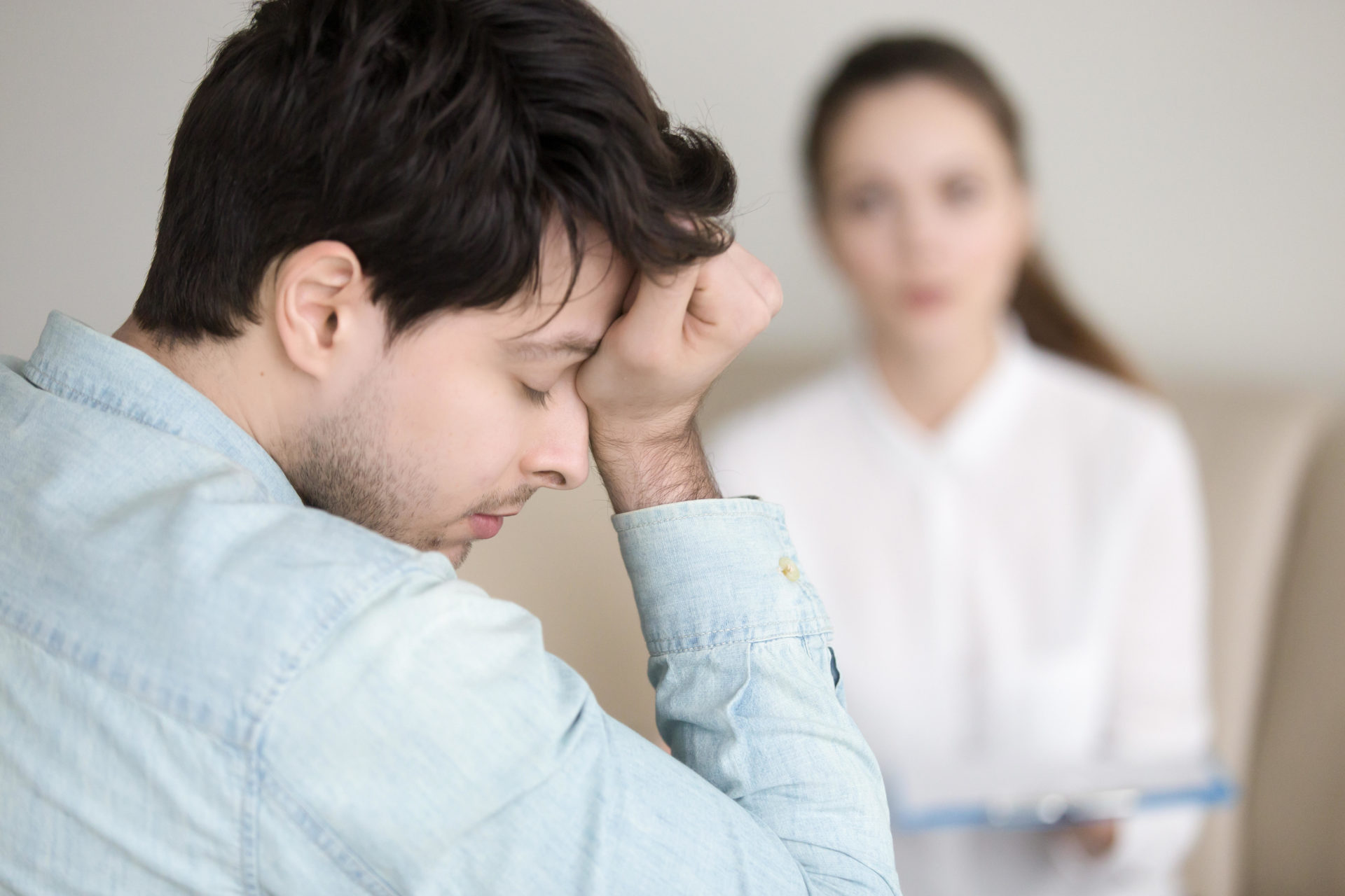 Tired young man having headache while working or visiting doctor.