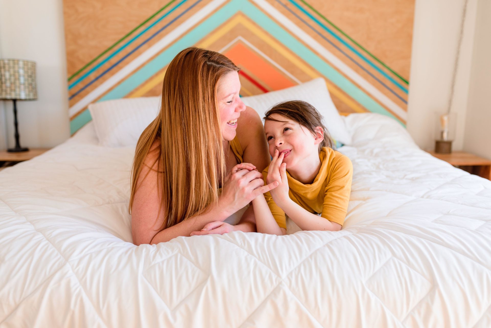 Portrait of a mother and daughter lying on a bed talking..