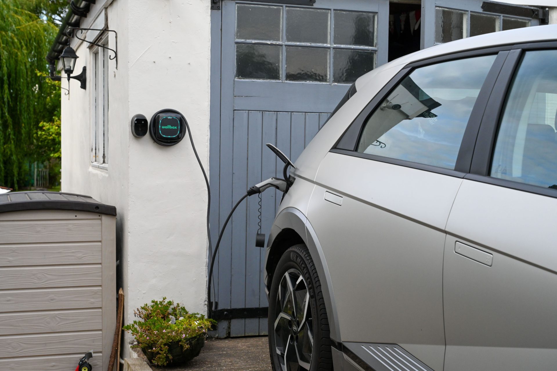 2K22PX6 Hyundai Ioniq 5 charging at home, EV wall charger outside a rural garage wallbox charger