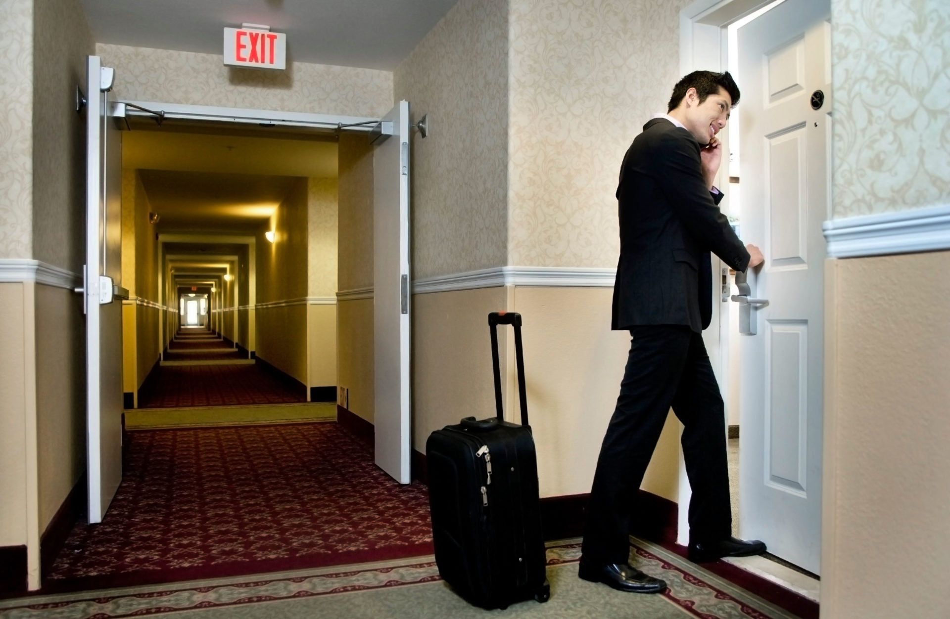 Businessman using cell phone and entering hotel room. Image: Alamy