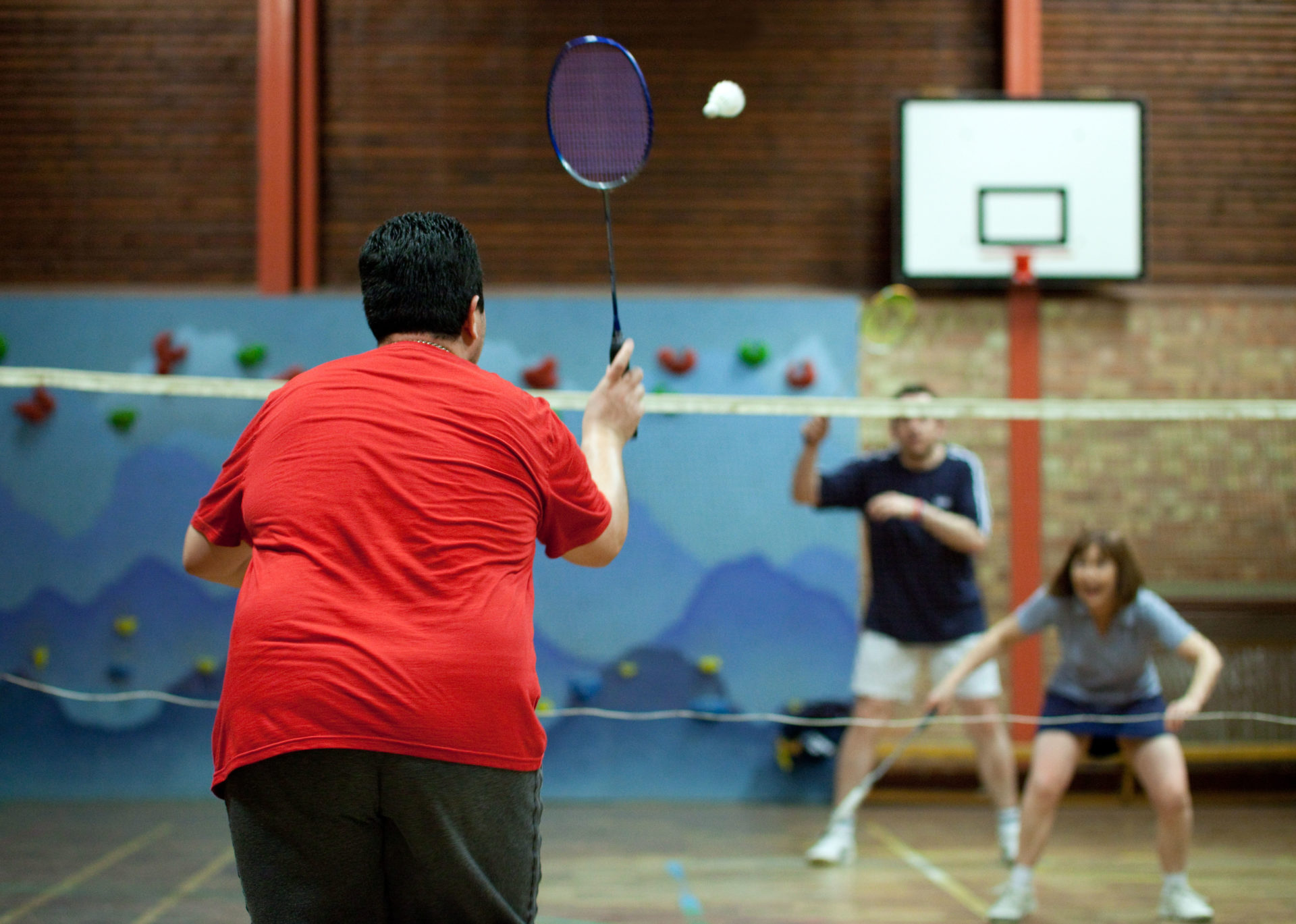 Body diversity UK; An overweight man playing badminton for exercise, UK. 