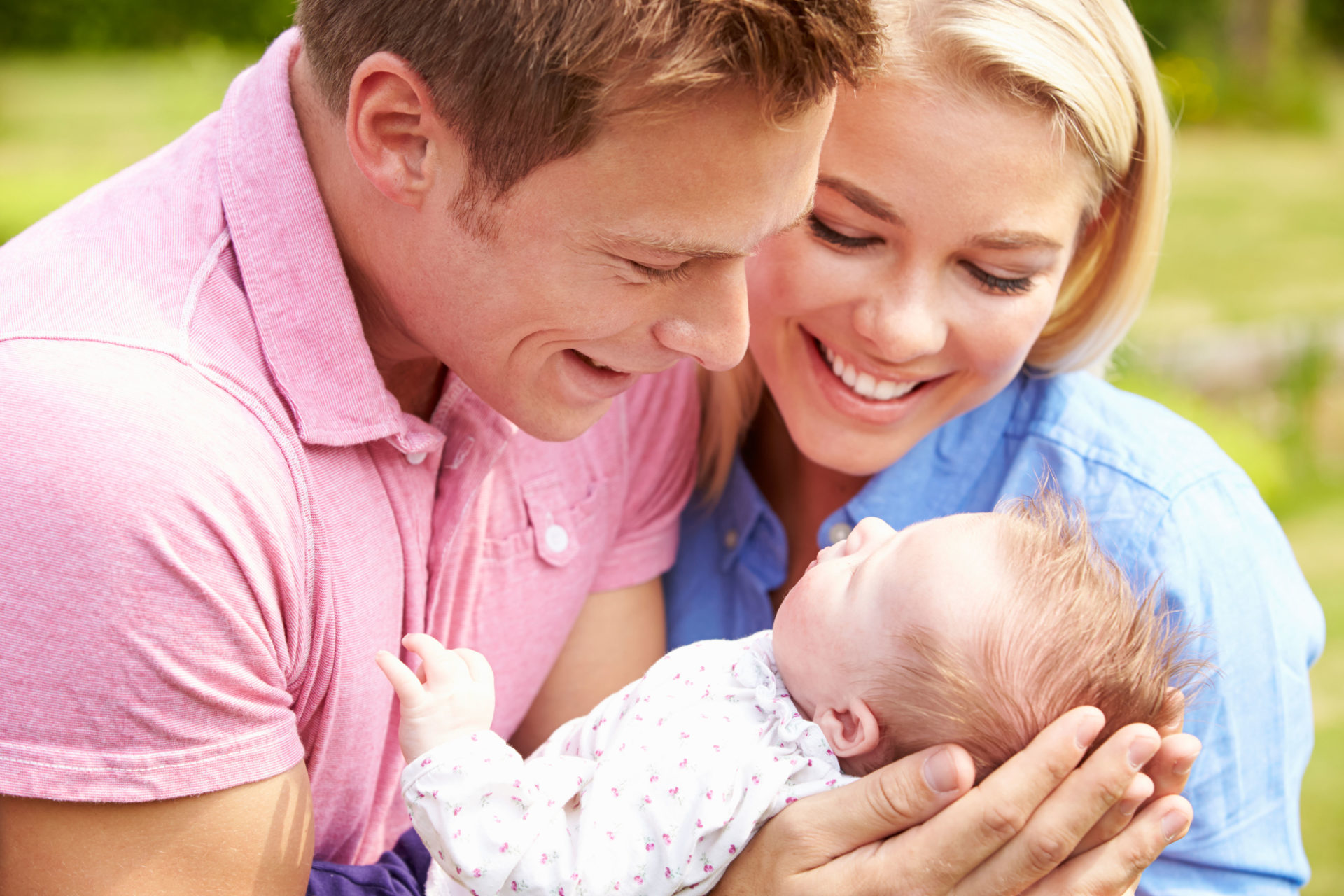 Proud Parents Holding Baby Daughter In Garden.