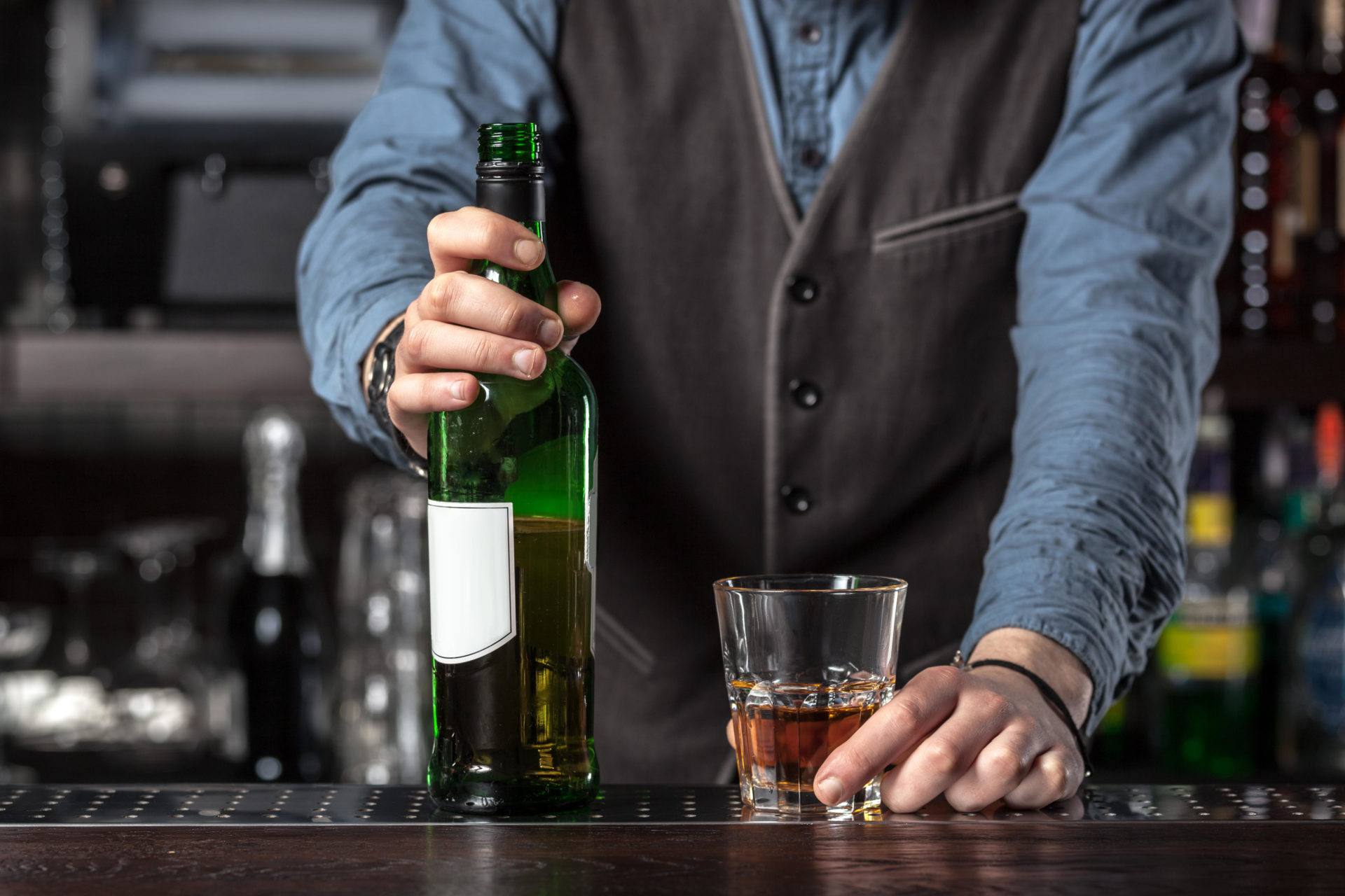 Barman giving whiskey glass with booze and bottle- concept image.