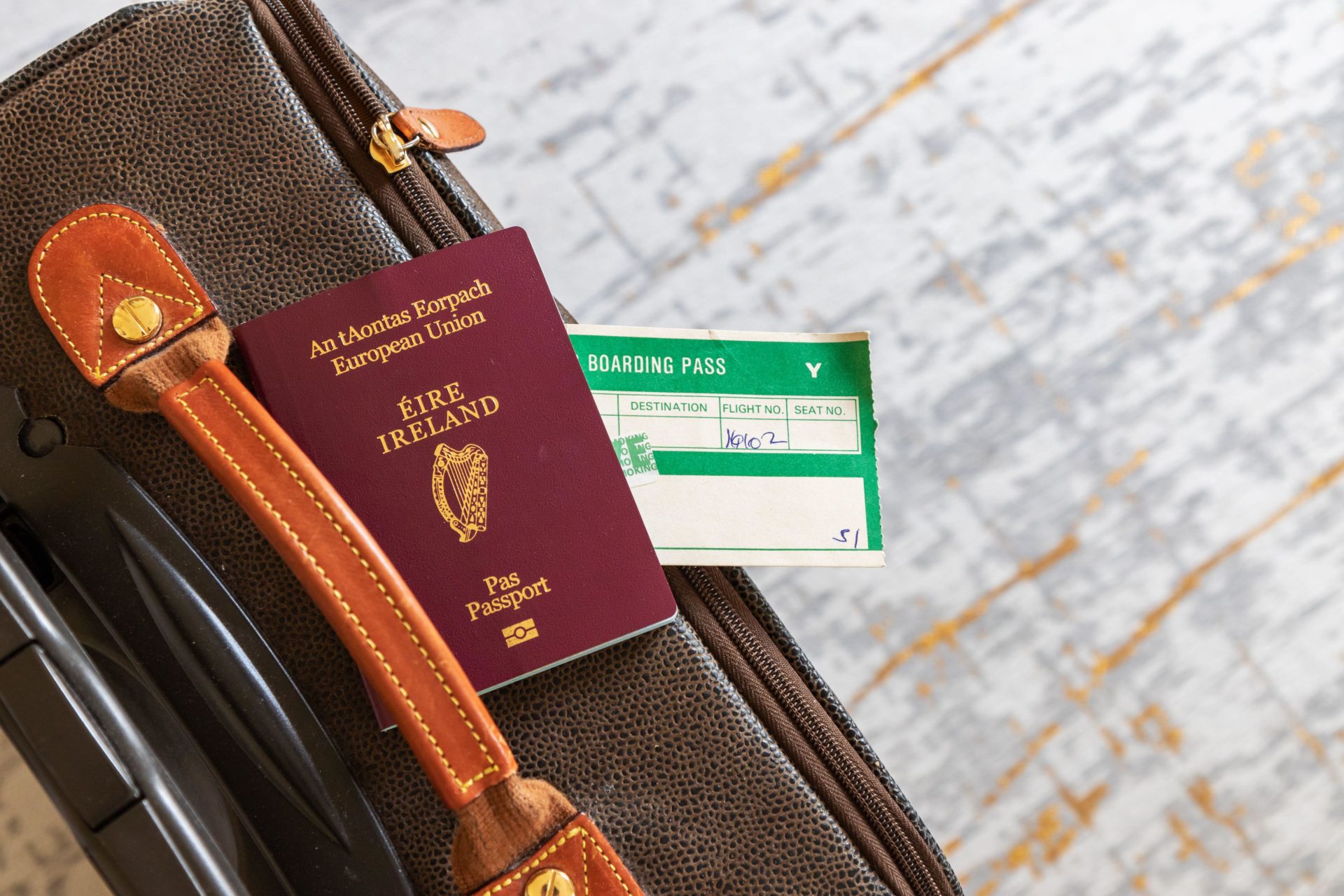 Irish passport with airplane boarding pass on suitcase.