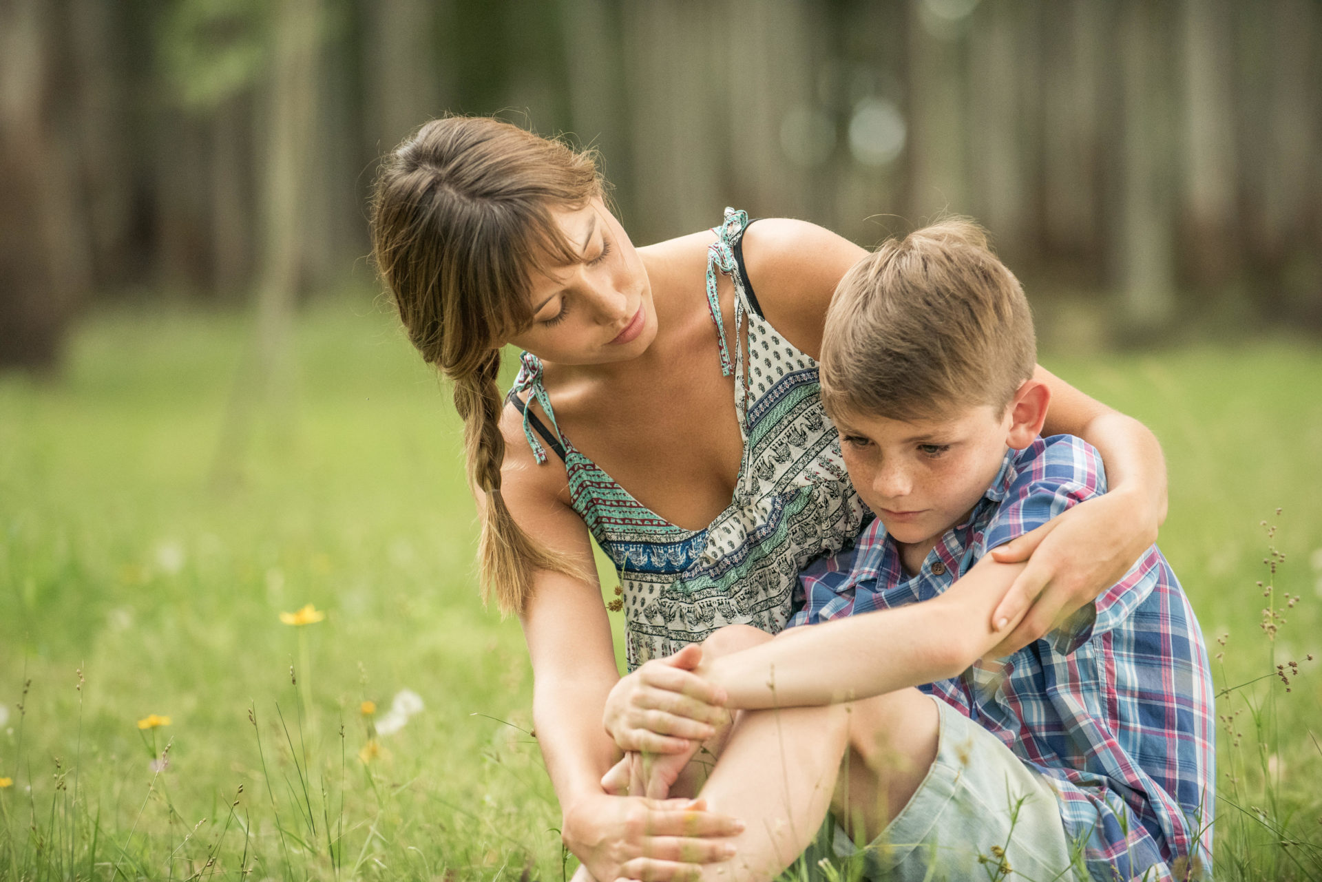 Mother comforting son outdoors.