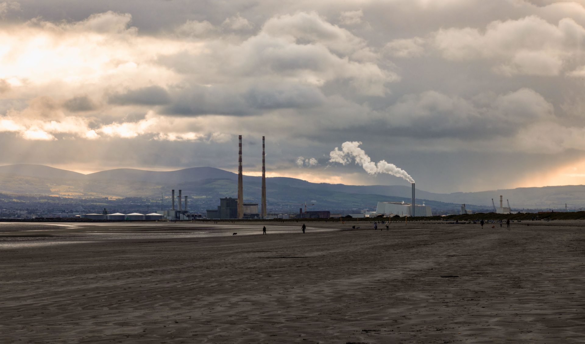 Light breaks through dark clouds on gloomy day at Dollymount Strand beach.