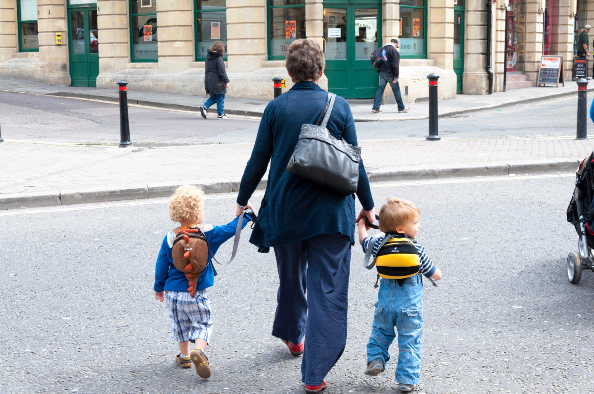 Crossing the road with young children in Bath, Somerset, England, UK.