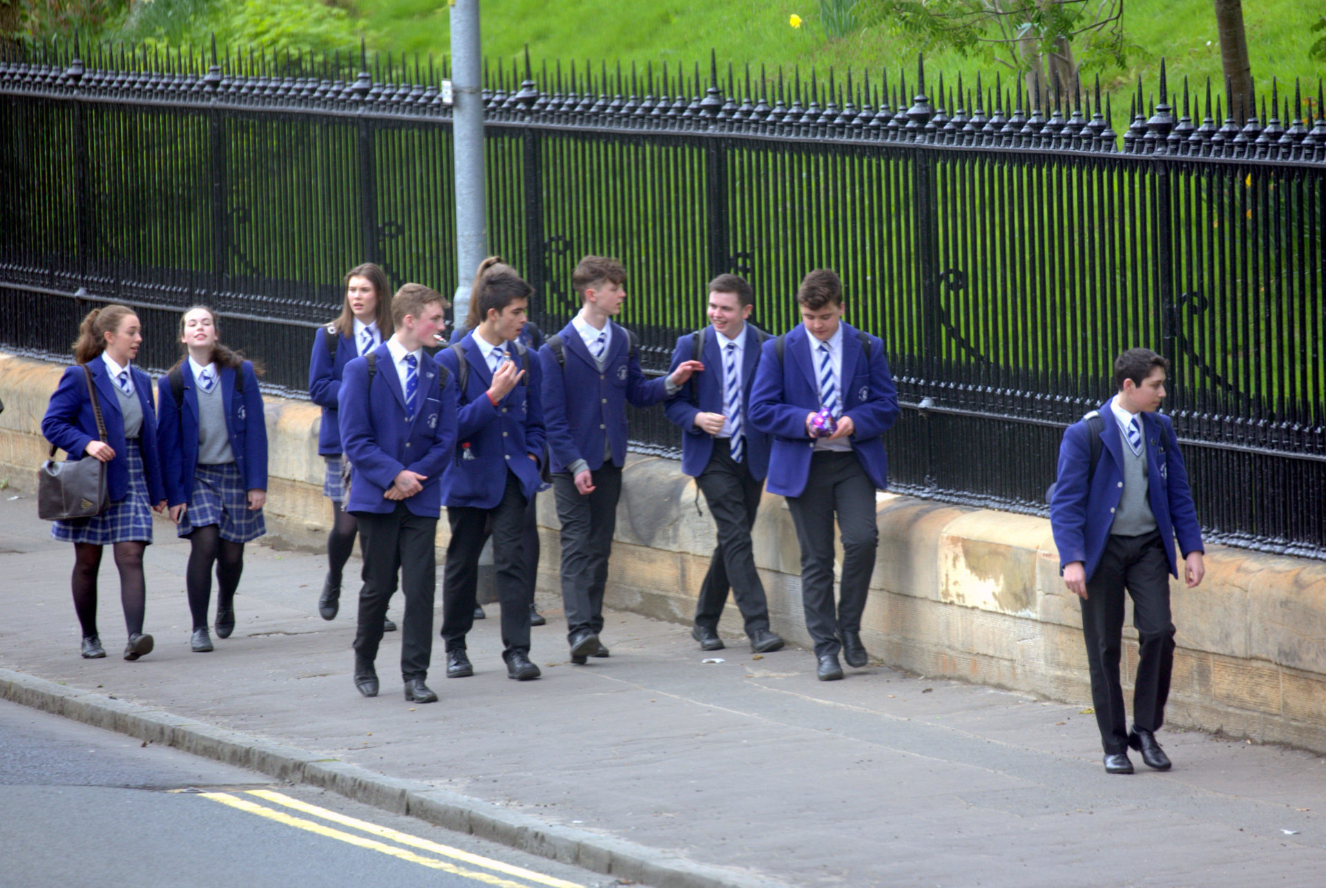 British school children on street messing about walking home from school the high school of Glasgow.