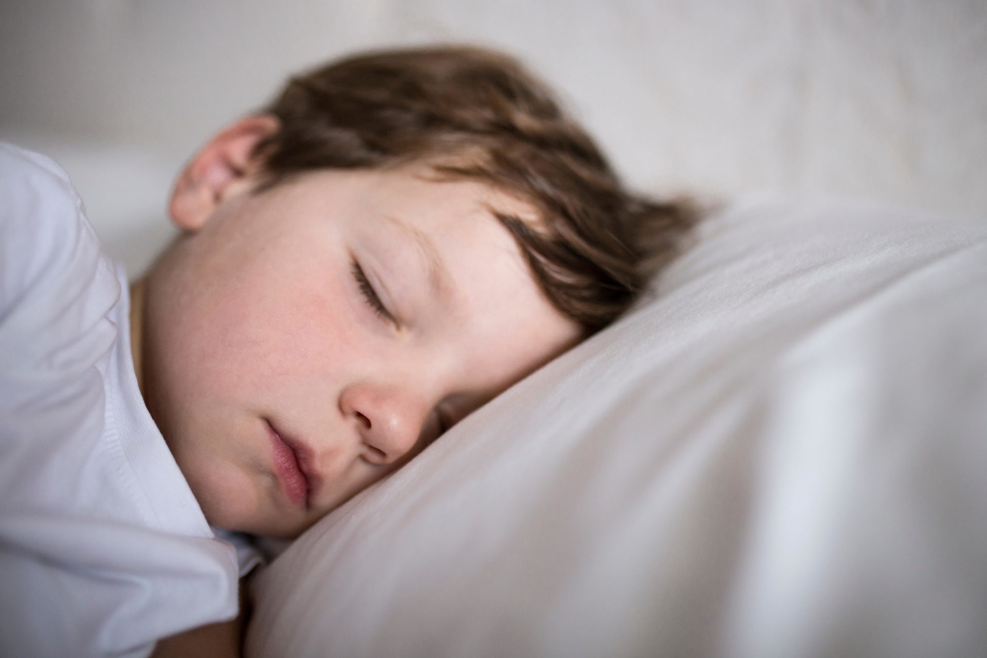 Toddler boy sleeping on bed.