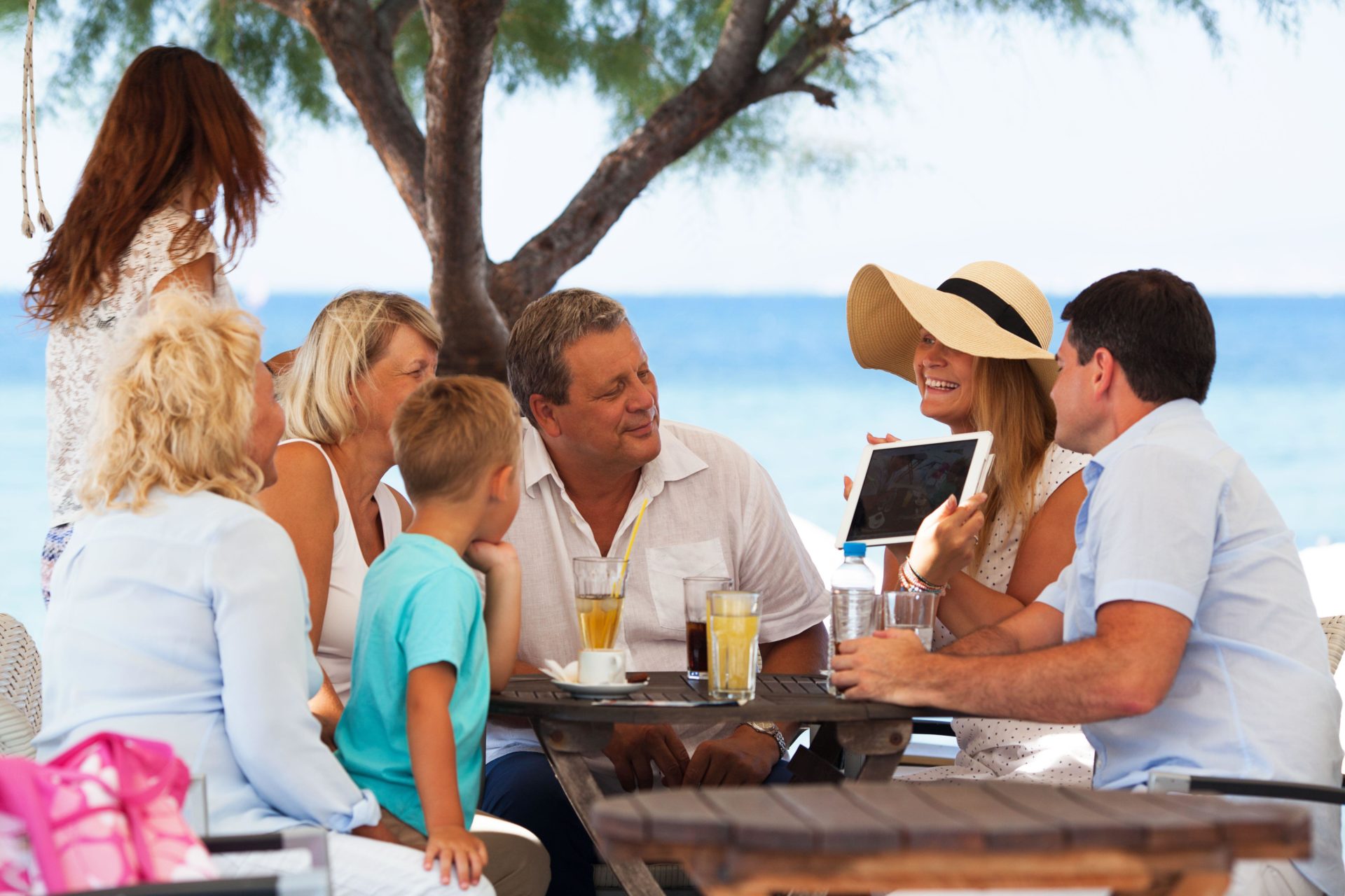 Family looking at photo on touch pad in outdoor cafe.