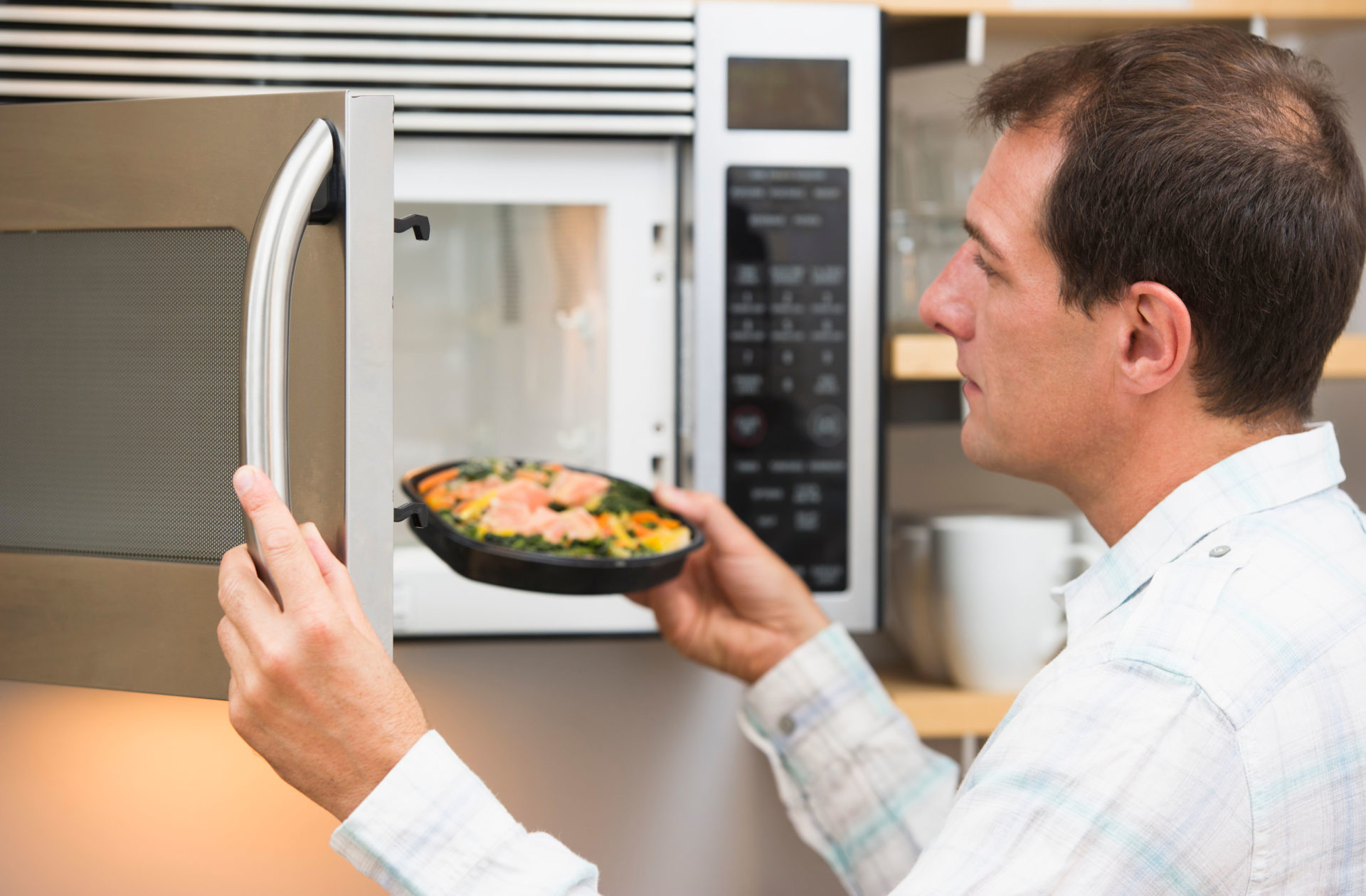 C6E327 USA, New Jersey, Jersey City, Man inserting meal in microwave oven