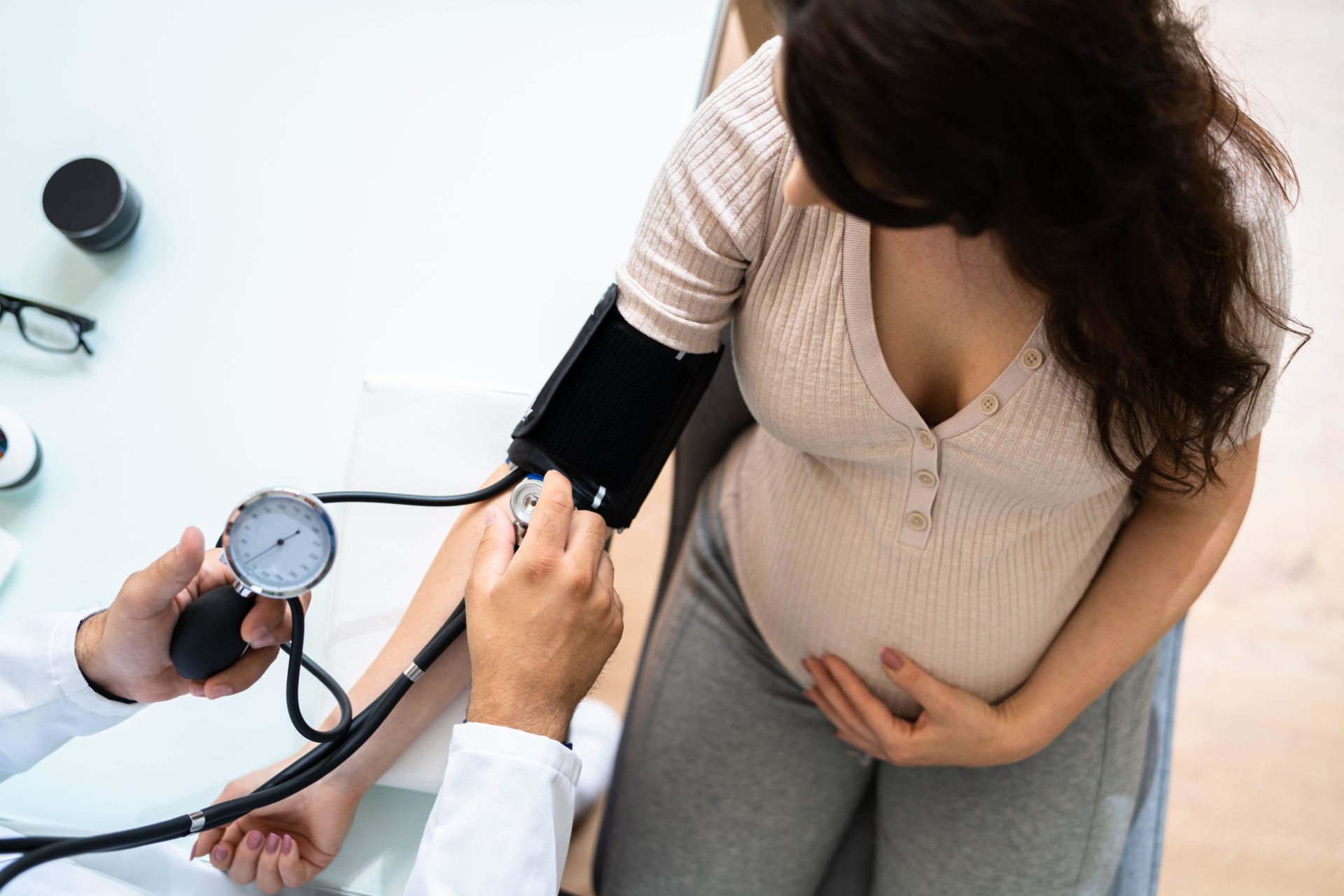 Close-up Of Male Doctor Measuring Blood Pressure Of Pregnant Woman In Clinic.