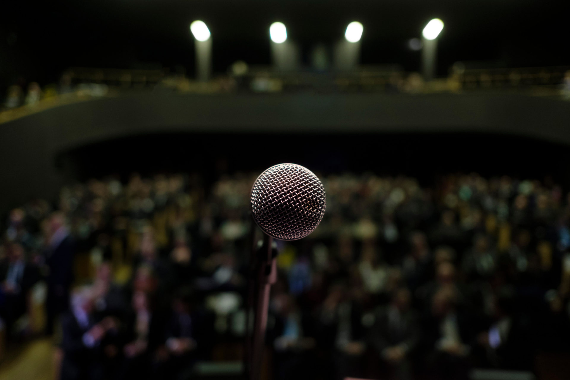 Microphone on stage in front of a crowd. 