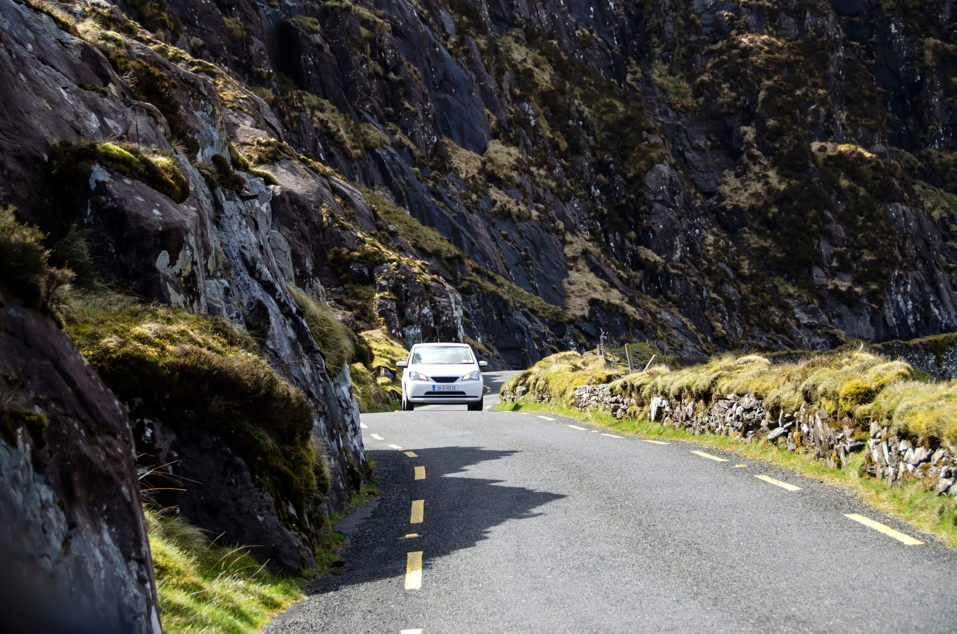 Auto on narrow two-way road descending the Conor Pass from Dingle town to Dunmore Head, Dingle Peninsula, County Kerry, Ireland.