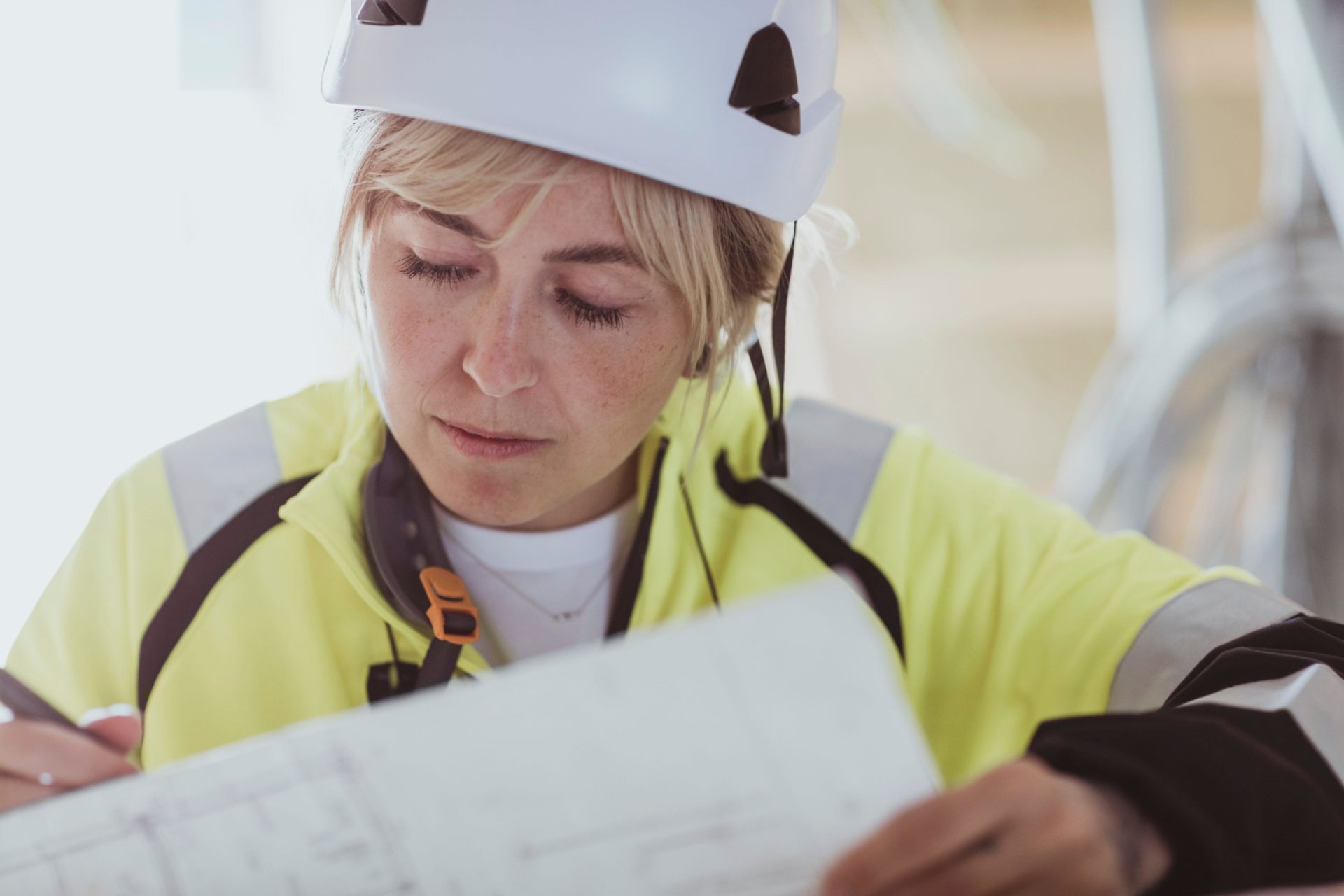 Female builder analyzing floor plan while working at construction site.