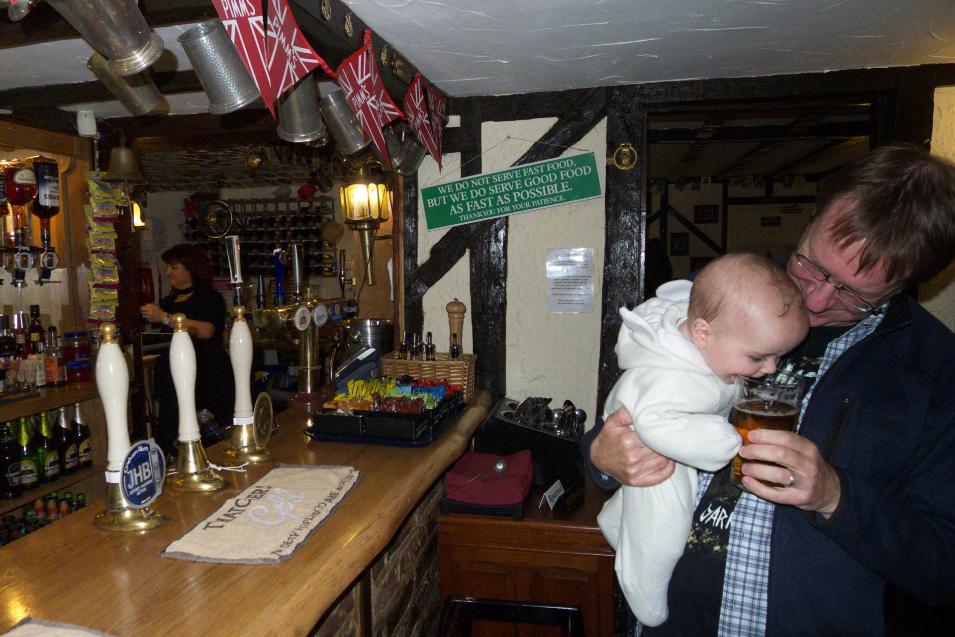 A baby drinking beer in a pub in England. 