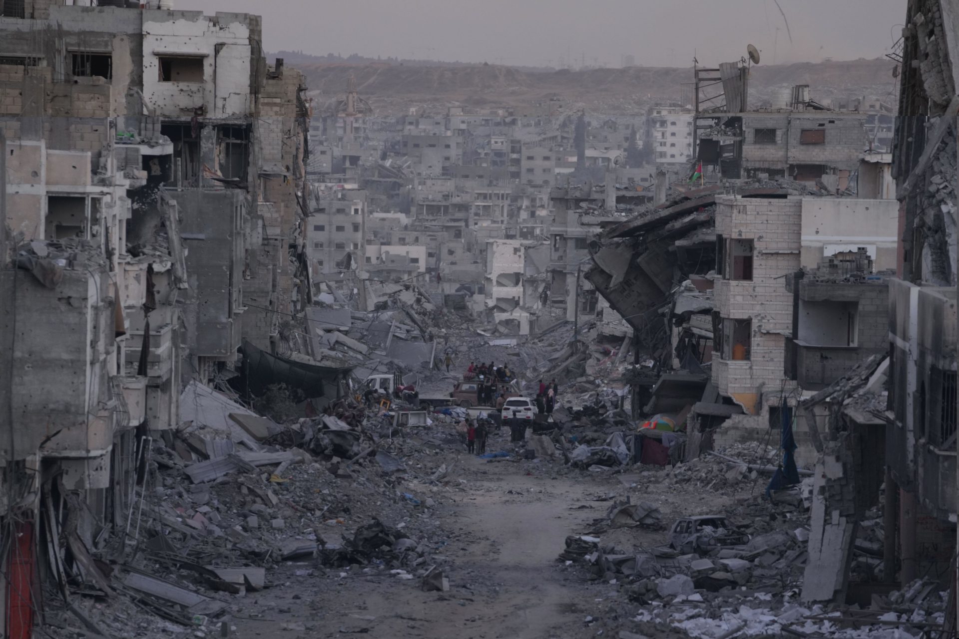 Palestinians walk among destroyed buildings in Gaza City.