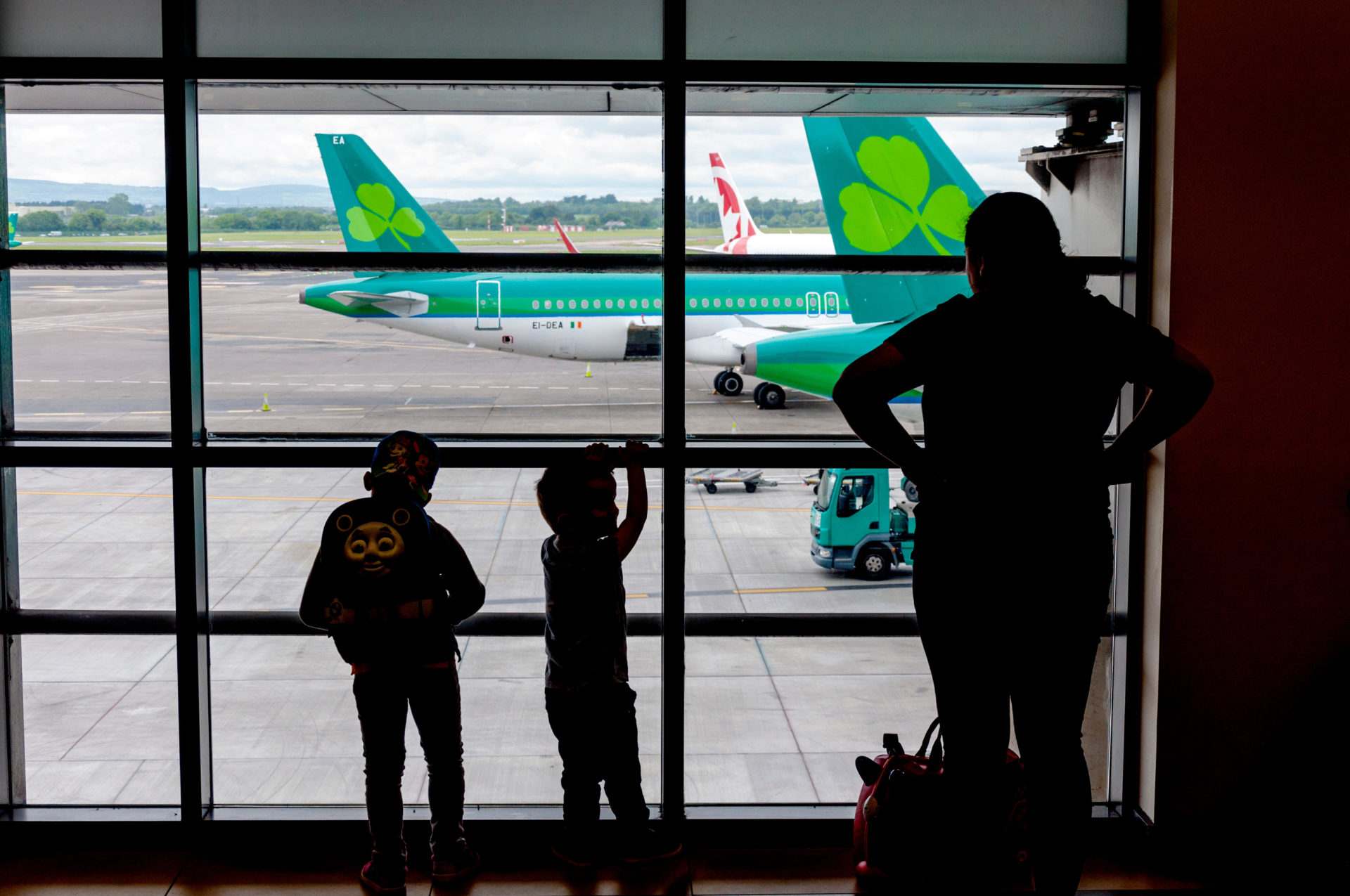 J97WME Dublin Airport, Ireland. Children watch aircraft from a terminal one window.