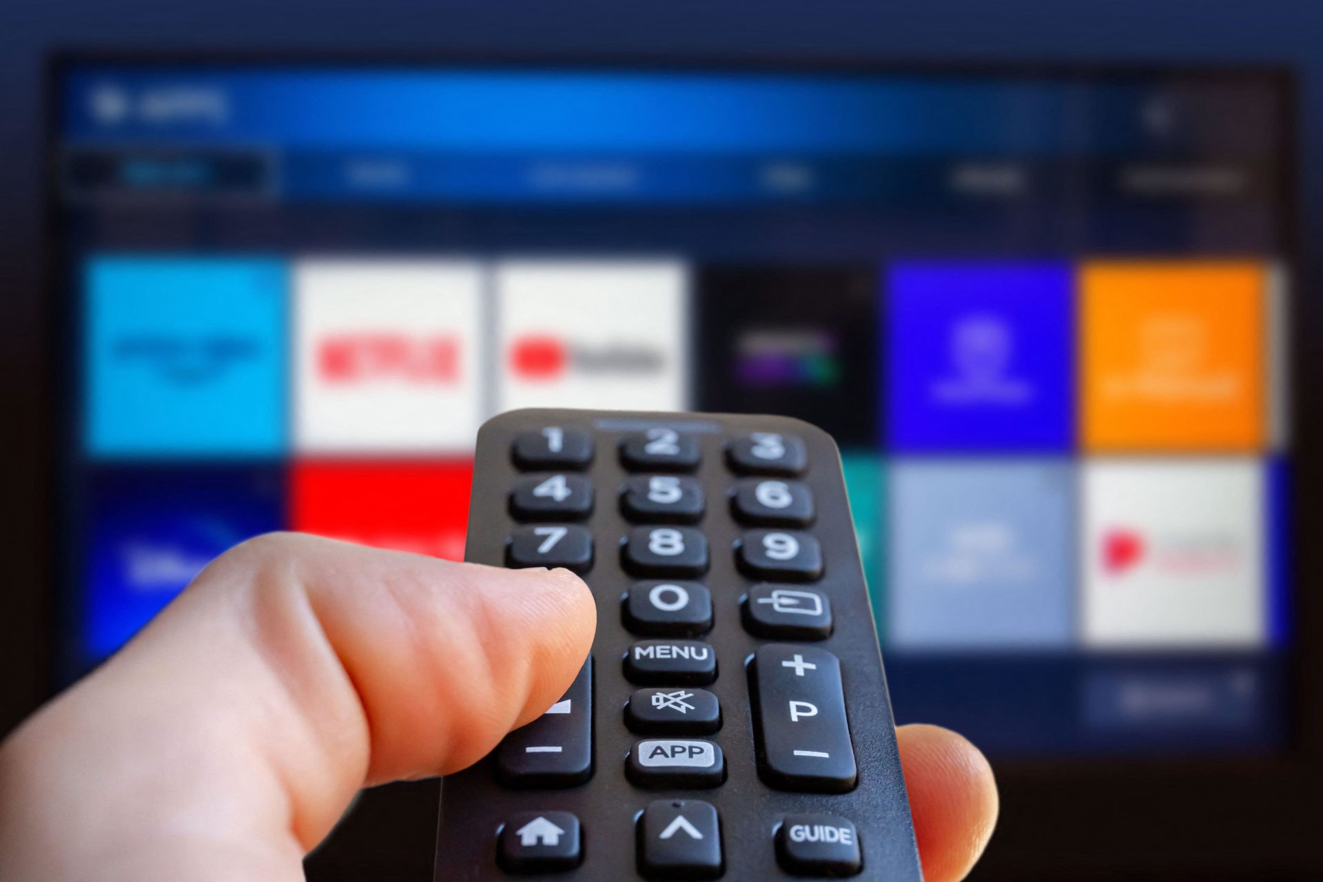 Dodgy boxes: A man is holding a remote control of a smart TV in his hand. In the background you can see the television screen with streaming entertainment apps for