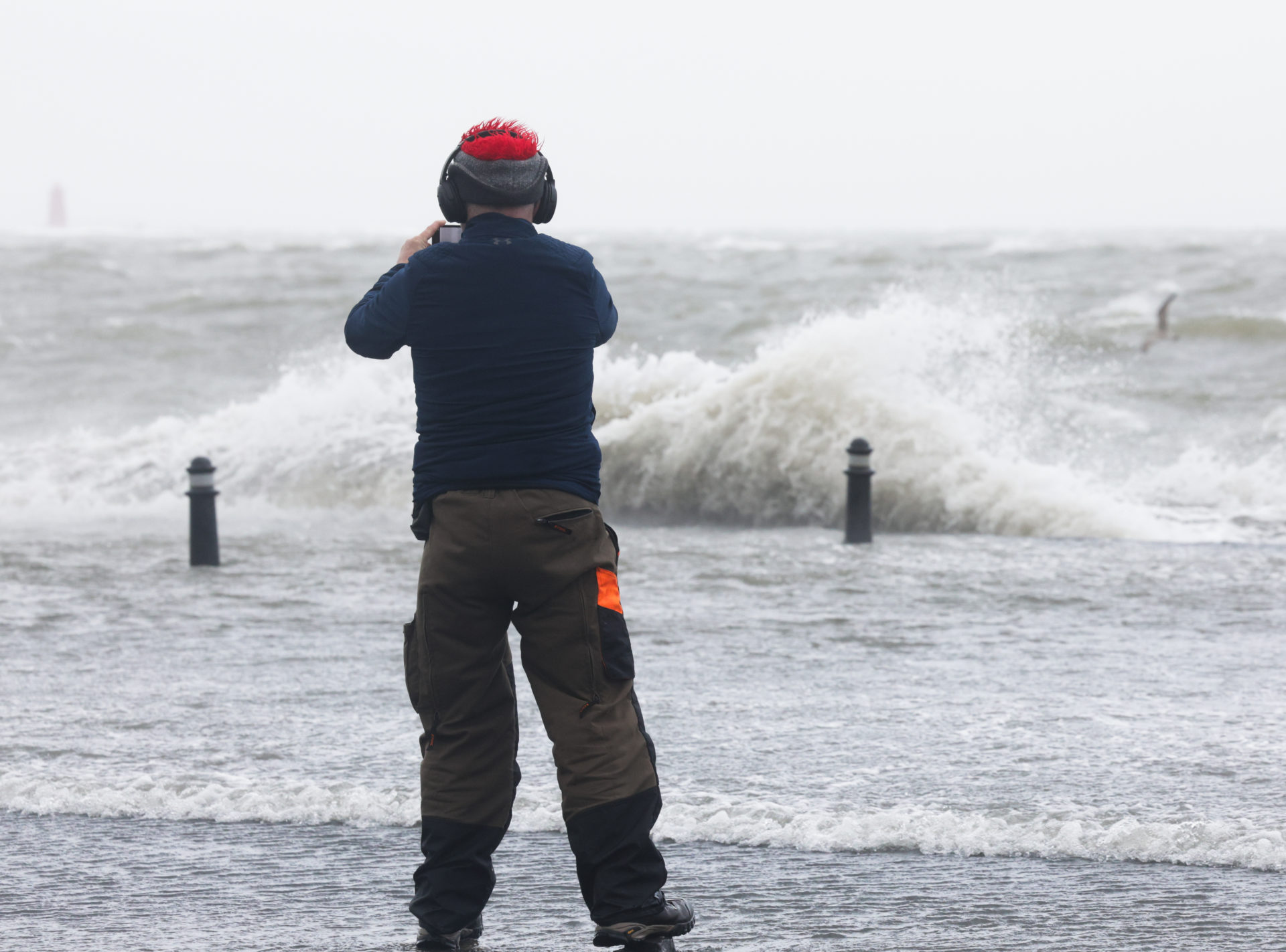 05/02/2026 Dublin, Ireland. A walker stops to take pictures of high waves and sea spray at Clontarf today, as an Orange Weather warning comes into place for Dublin this afternoon. Met Eireann has warned that heavy rain today could lead to more flooding in the Dublin area today and tomorrow. Photograph: Sasko Lazarov / © RollingNews.ie