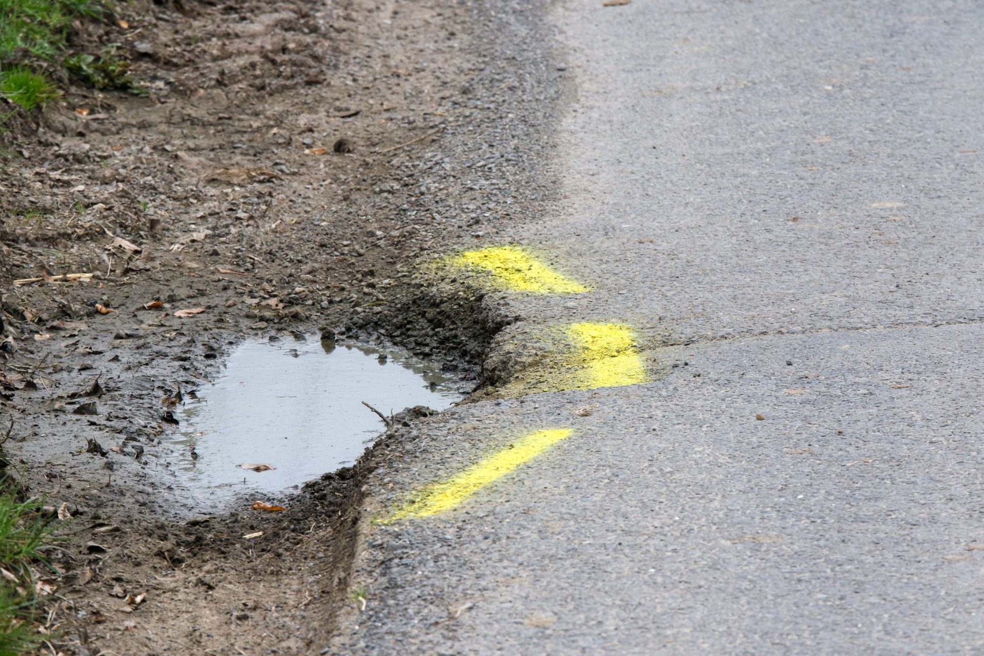 2BF29F8 Yellow lines marking a pothole needing repair at the side of a rural country road in Northern Ireland.