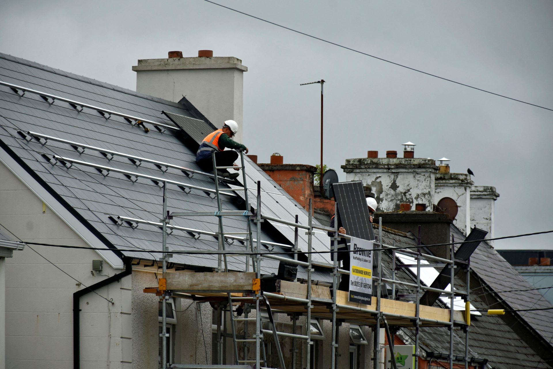 2XDYHRA Workers installing solar panels on a roof in Ardara, County Donegal, Ireland.